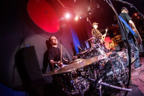 Musician playing drums on stage, rock music concert.